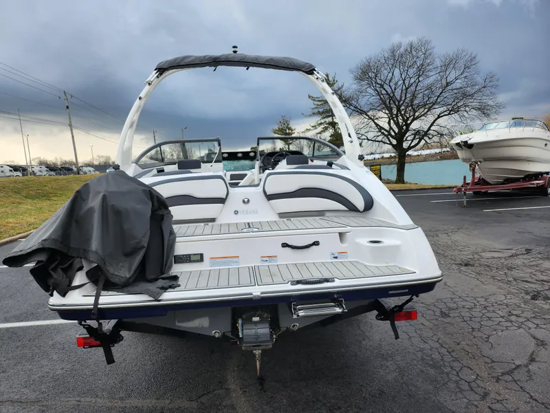 Slide: The Image of 2017 Yamaha Boats AR190, rear view, parked on asphalt near water and trees. - 2