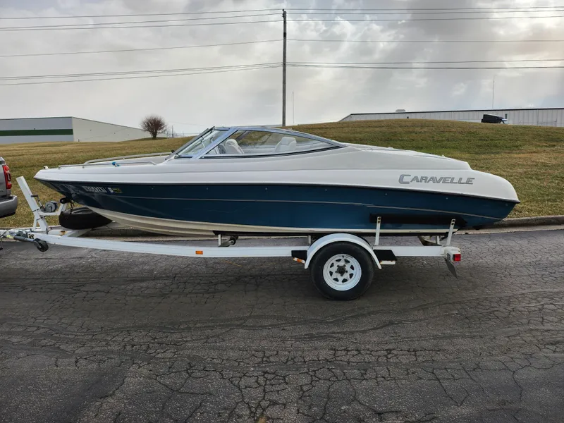 Slide: The Image of 1994 Caravelle 1900 SE boat on trailer, parked on asphalt road, cloudy sky background. - 5