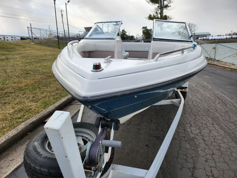 Slide: The Image of 1994 Caravelle 1900 SE boat on trailer, parked on paved road near grassy area. - 7