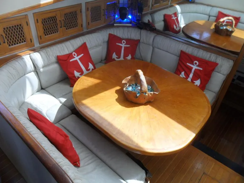 Slide: The Image of Cozy 1986 Symbol Yachtfisher dining area with anchor-themed pillows and wooden table. - 13