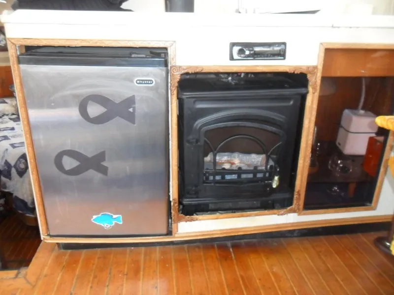 Slide: The Image of 1986 Symbol Yachtfisher interior with fridge, stove, and storage on wooden flooring. - 14