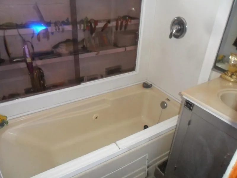 Slide: The Image of 1986 Symbol Yachtfisher bathroom with beige bathtub and fishing gear display. - 24