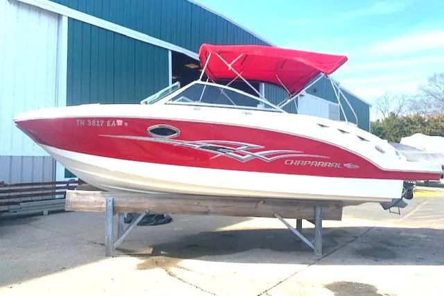 The Image of 2010 Chaparral Sunesta 224 boat with red and white design, docked outdoors. - 0