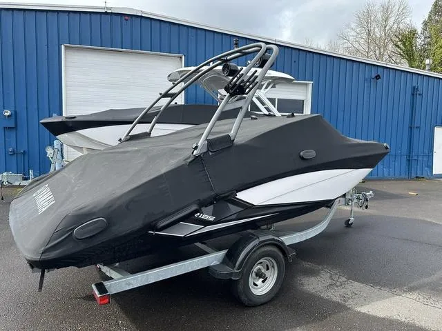 Slide: The Image of 2018 Yamaha Boats AR195 covered on trailer, parked outside blue building. - 3