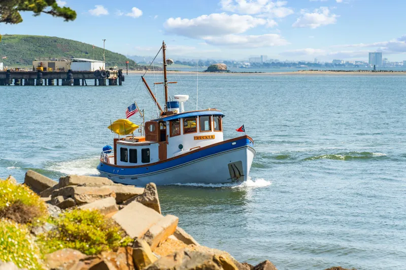 Slide: The Image of A 1987 Lord Nelson 37 Victory Tug navigating a scenic coastal waterway. - 1