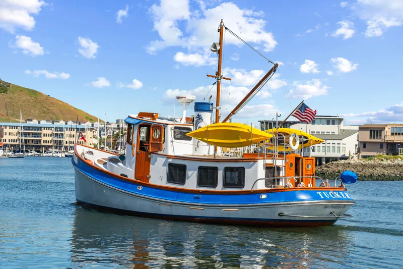 Slide: The Image of 1987 Lord Nelson 37 Victory Tug boat on calm water, with American flag and clear sky. - 24