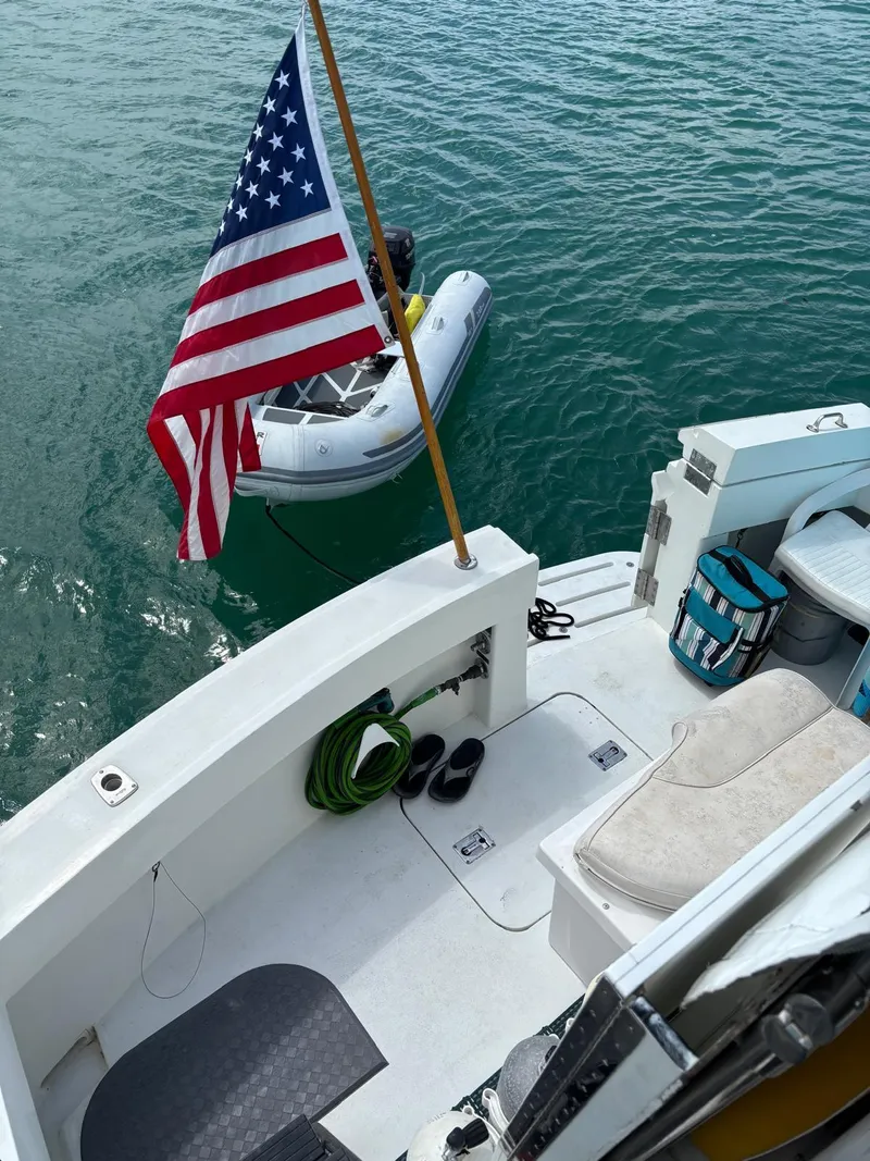 Slide: The Image of 1991 Hatteras 52 Cockpit Motor Yacht with American flag and inflatable boat on water. - 34