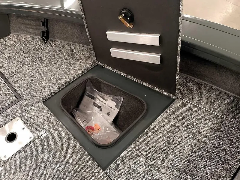 Slide: The Image of 2025 Ranger VX1988 WT boat storage compartment with carpeted interior and secure lock. - 20