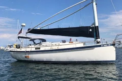 The Image of 1988 Nonsuch 33 sailboat with black sail cover, anchored in calm waters. - 0