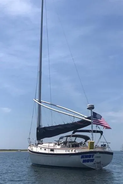 Slide: The Image of 1988 Nonsuch 33 sailboat with American flag, anchored under clear blue sky. - 1
