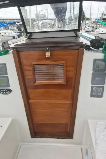 Slide: The Image of 1988 Nonsuch 33 sailboat cabin entrance with wooden door and lock, surrounded by navigation instruments. - 13
