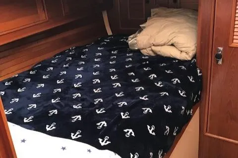 Slide: The Image of Cozy cabin bed in 1988 Nonsuch 33 sailboat with anchor-patterned blanket. - 18