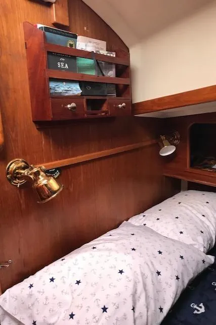 Slide: The Image of Cozy cabin interior of 1988 Nonsuch 33 sailboat with wooden shelves and nautical-themed bedding. - 20