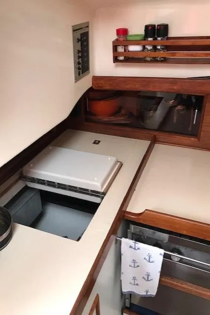 Slide: The Image of 1988 Nonsuch 33 yacht interior kitchen with stove, spice rack, and nautical-themed towel. - 23