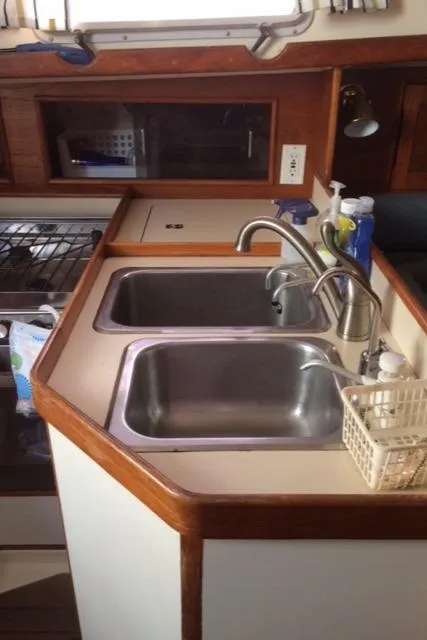 Slide: The Image of 1988 Nonsuch 33 yacht kitchen with dual sinks and wooden cabinetry. - 25