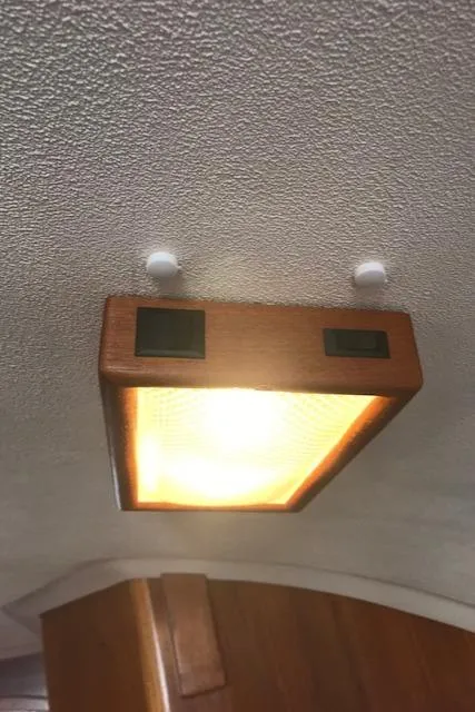 Slide: The Image of Ceiling light fixture inside 1988 Nonsuch 33 sailboat, featuring wooden frame and warm illumination. - 29