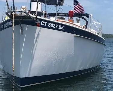 Slide: The Image of 1988 Nonsuch 33 sailboat with American flag, anchored on calm water. - 3
