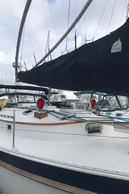 Slide: The Image of 1988 Nonsuch 33 sailboat docked at marina, featuring sleek design and dark sail cover. - 4