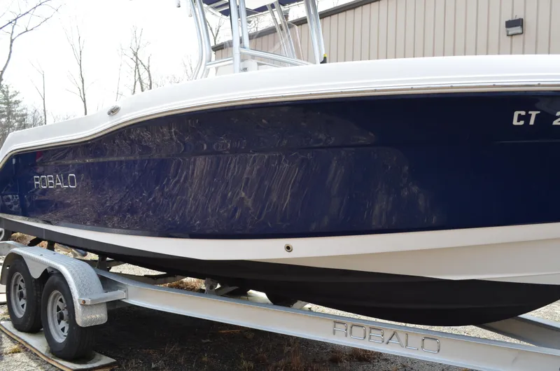 Slide: The Image of 2018 Robalo R200 Center Console boat on trailer, blue hull, parked outdoors. - 48