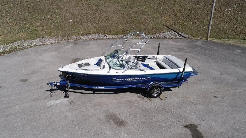 Slide: The Image of 2009 Moomba Outback SK boat on trailer, blue and white design, parked on pavement. - 5