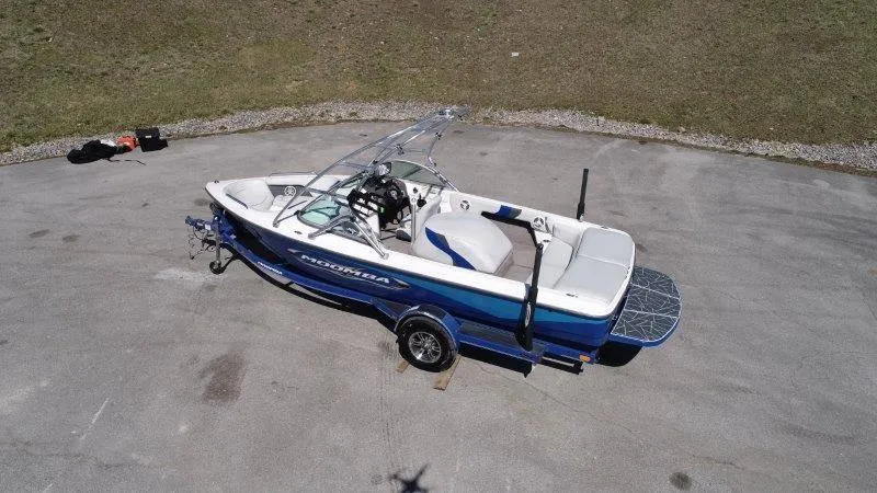 Slide: The Image of 2009 Moomba Outback SK boat on trailer, blue and white, parked on concrete surface. - 6