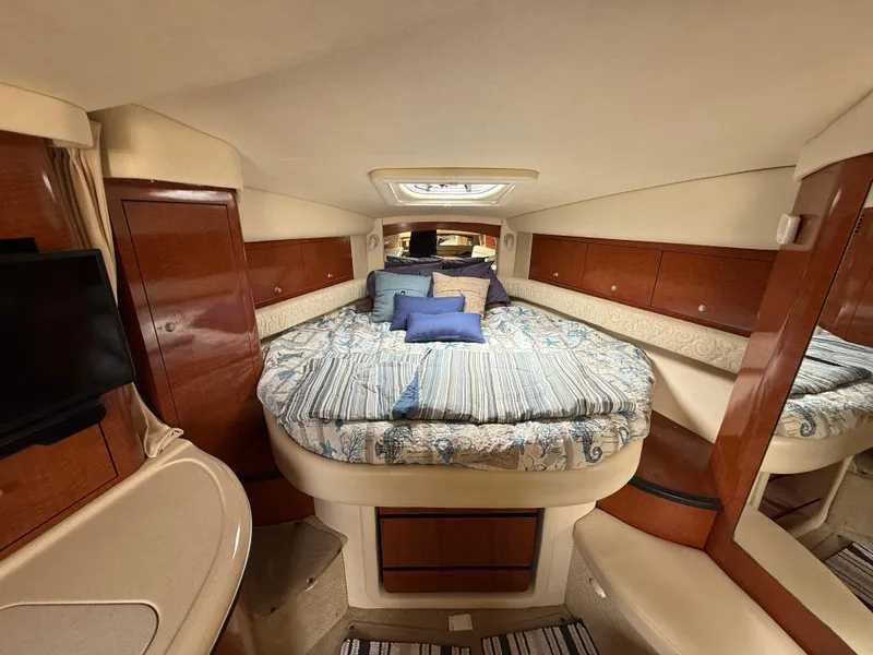 Slide: The Image of 2005 Sea Ray 340 Sundancer cabin with cozy bed, wooden cabinets, and a small TV. - 16
