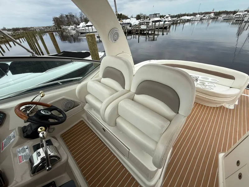Slide: The Image of 2005 Sea Ray 340 Sundancer cockpit with dual seats and wooden deck, docked by a serene marina. - 30