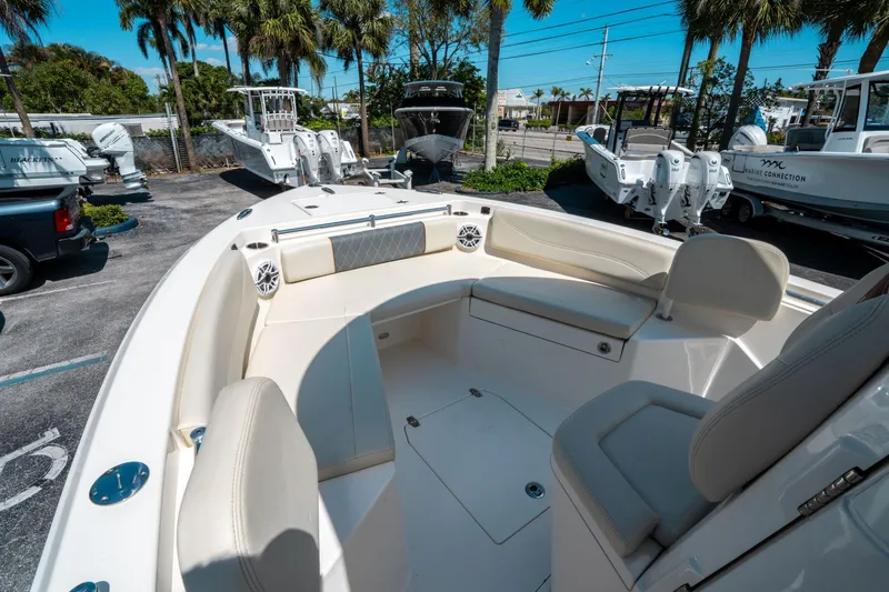 Slide: The Image of 2023 Cobia 240 CC boat interior with seating, parked among palm trees. - 26