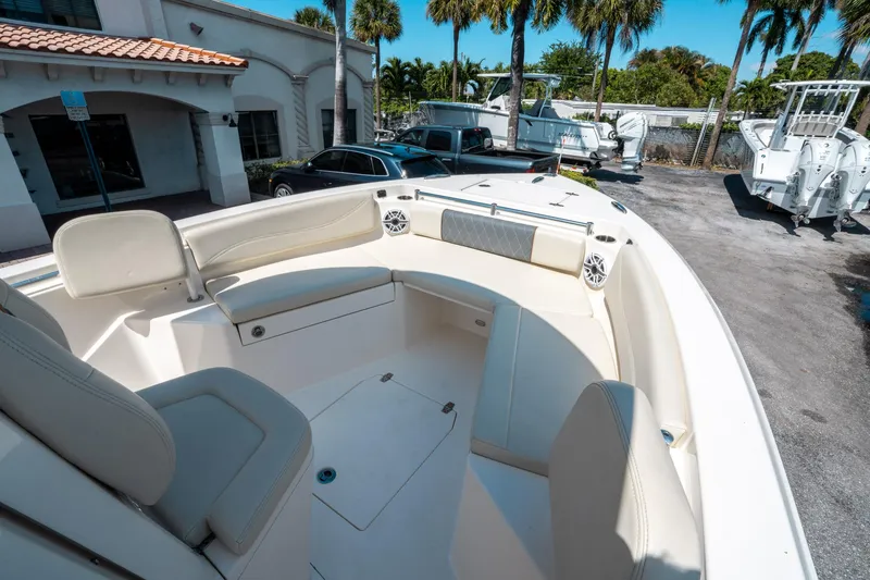 Slide: The Image of 2023 Cobia 240 CC boat interior with cushioned seating and speakers, parked outdoors. - 27