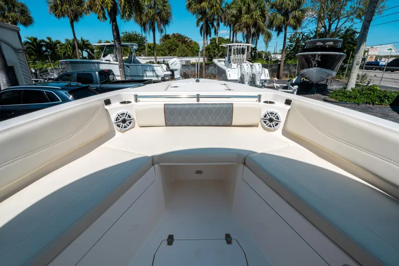 Slide: The Image of 2023 Cobia 240 CC boat interior with seating and speakers, surrounded by palm trees. - 28