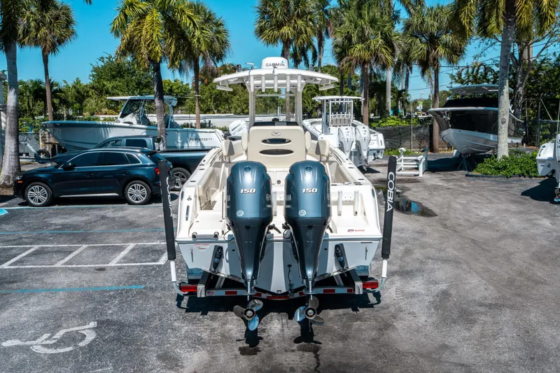 Slide: The Image of 2023 Cobia 240 CC boat with dual engines in a sunny marina setting. - 3