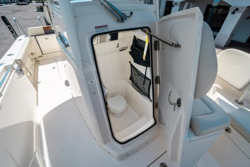 Slide: The Image of 2023 Cobia 240 CC boat interior with open door revealing compact restroom. - 30
