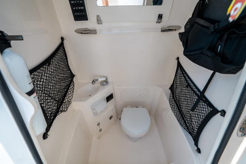 Slide: The Image of 2023 Cobia 240 CC boat interior with compact bathroom, sink, and storage nets. - 31