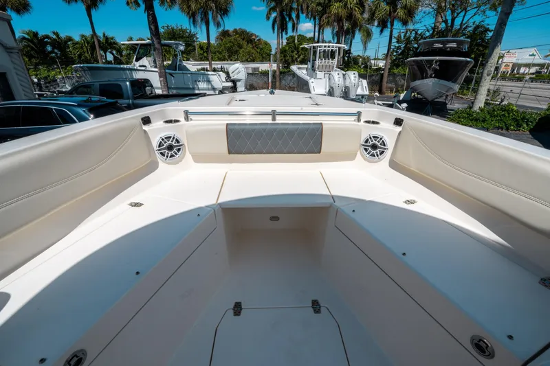 Slide: The Image of 2023 Cobia 240 CC boat interior with seating and speakers, surrounded by palm trees. - 32
