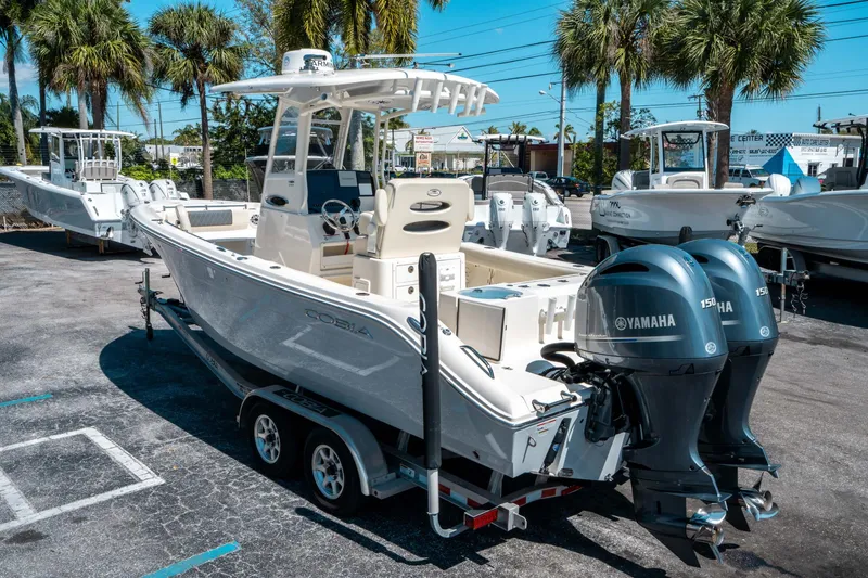 Slide: The Image of 2023 Cobia 240 CC boat with dual Yamaha engines, parked outdoors. - 4