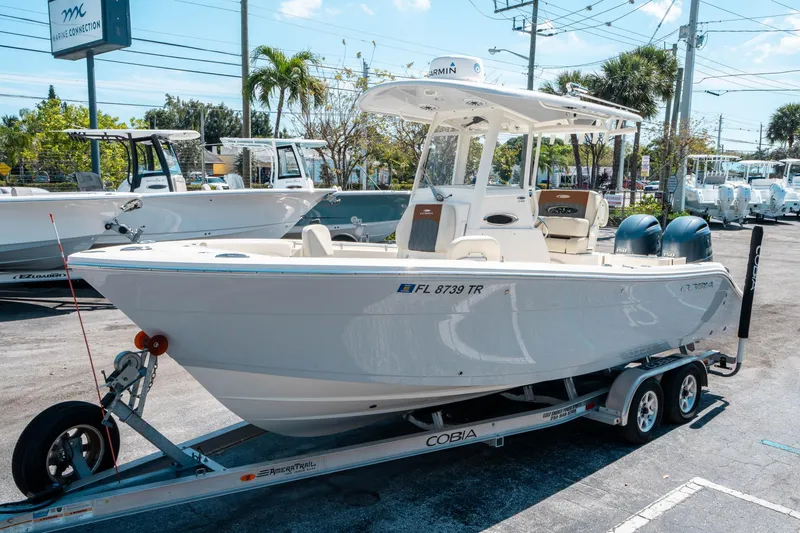 Slide: The Image of 2023 Cobia 240 CC boat on trailer at dealership, sunny day. - 6