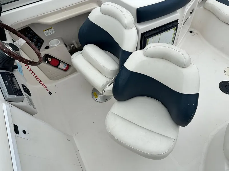 Slide: The Image of 2004 Godfrey Hurricane 260 Sun Deck boat interior with dual white and blue captain chairs. - 11