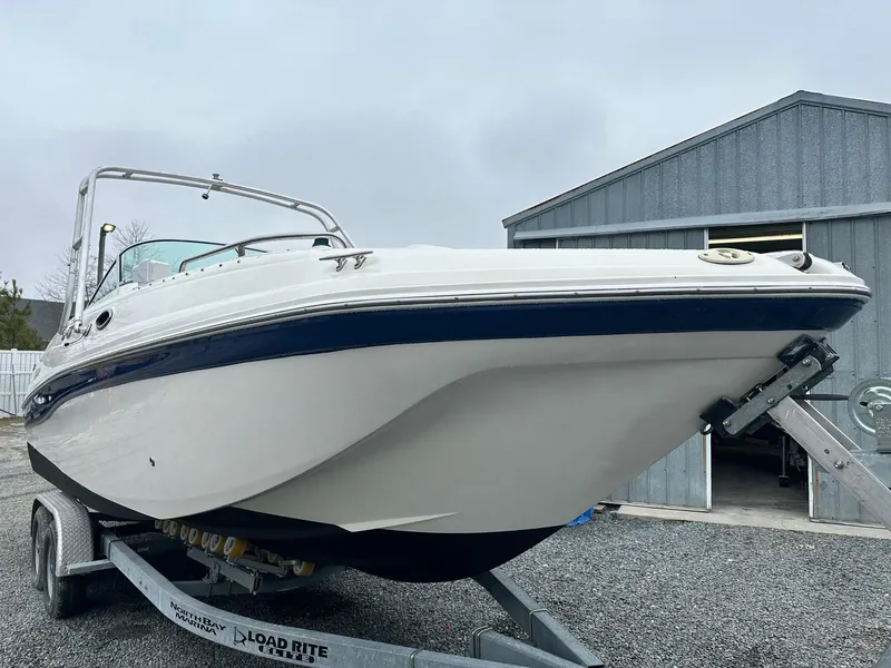 Slide: The Image of 2004 Godfrey Hurricane 260 Sun Deck boat on trailer near metal building. - 2