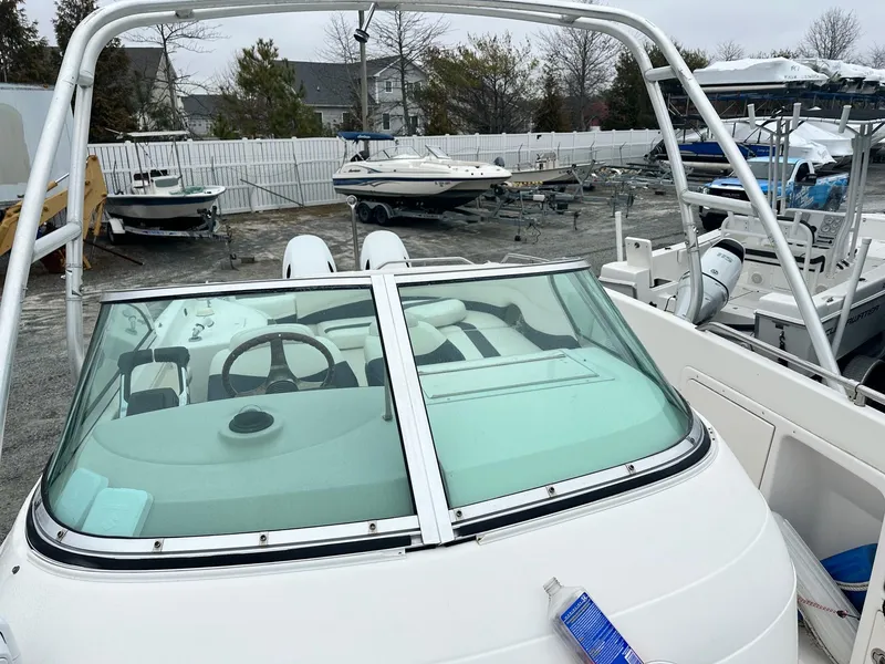 Slide: The Image of 2004 Godfrey Hurricane 260 Sun Deck boat in storage yard, featuring dual consoles and windshield. - 6