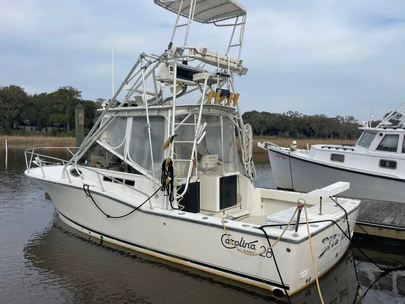 Slide: The Image of 2003 Carolina Classic 28 boat docked in a marina, featuring a tower and fishing equipment. - 0