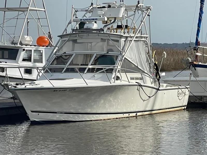 Slide: The Image of 2003 Carolina Classic 28 boat docked in marina, featuring a sturdy design and fishing equipment. - 1
