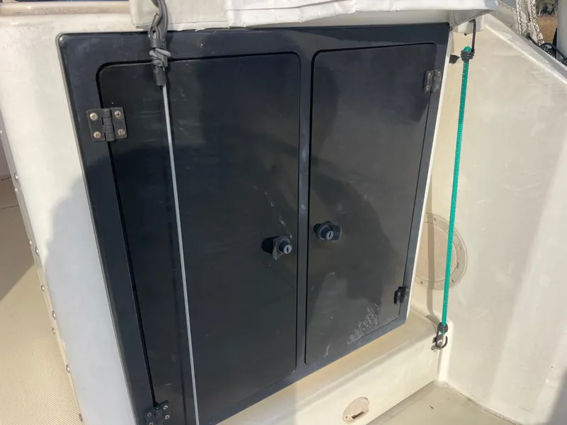 Slide: The Image of Storage compartment on a 2003 Carolina Classic 28 boat, featuring dual black doors. - 11