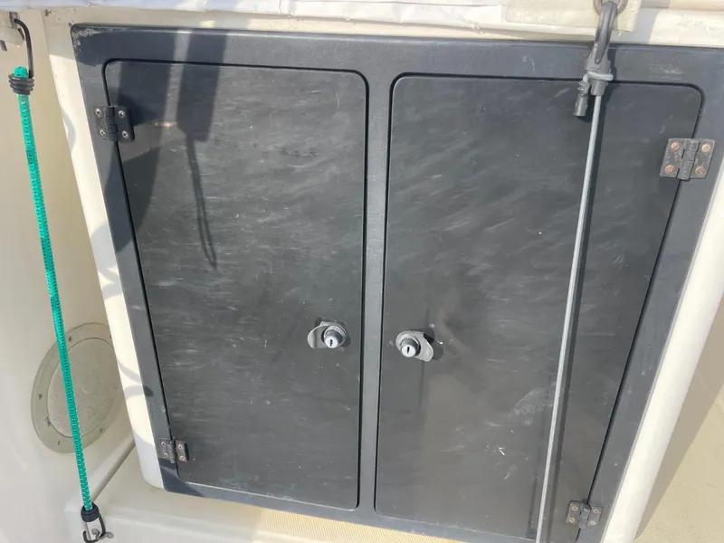 Slide: The Image of Storage compartment on a 2003 Carolina Classic 28 boat, featuring dual black doors. - 12