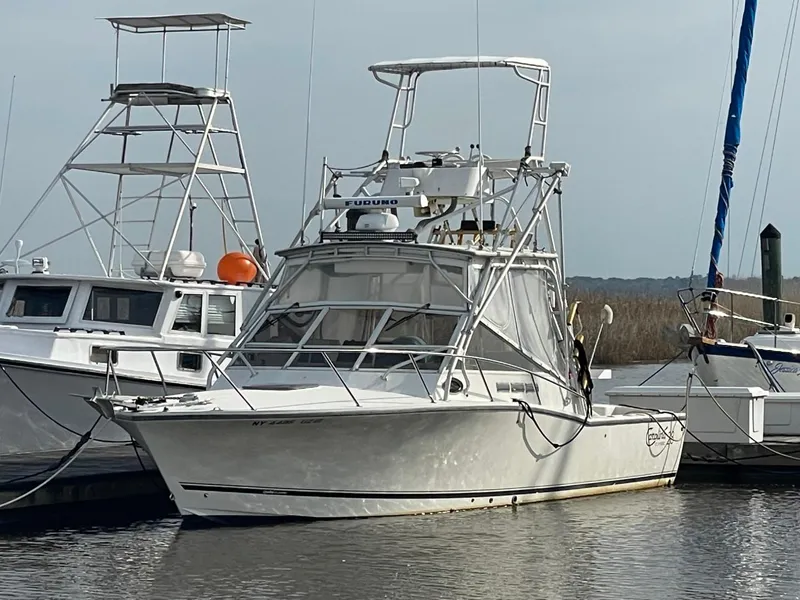 Slide: The Image of 2003 Carolina Classic 28 boat docked at marina, featuring a white hull and tower. - 2