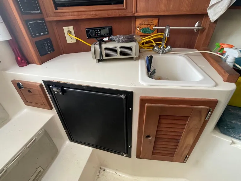 Slide: The Image of 2003 Carolina Classic 28 boat interior with sink, mini fridge, and wooden cabinetry. - 20