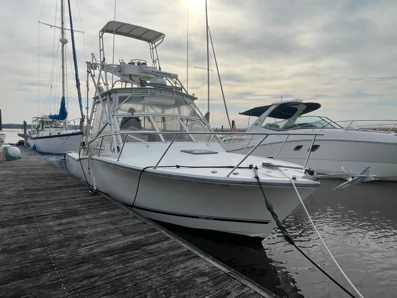 Slide: The Image of 2003 Carolina Classic 28 boat docked at marina, overcast sky, other boats nearby. - 3
