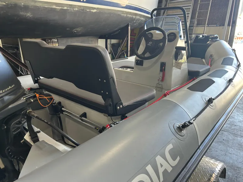 Slide: The Image of 2025 Zodiac Open 4.2 inflatable boat, gray interior, steering console, docked indoors. - 7