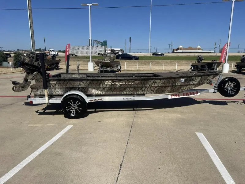 Slide: The Image of 2019 Pro-Line BTX 1848 boat on trailer, camo design, pre-owned, parked outdoors. - 6