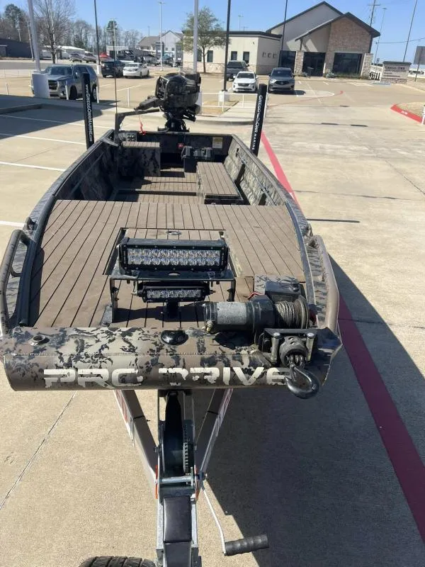 Slide: The Image of 2019 Pro-Line BTX 1848 boat on trailer in parking lot, featuring camouflage design. - 8