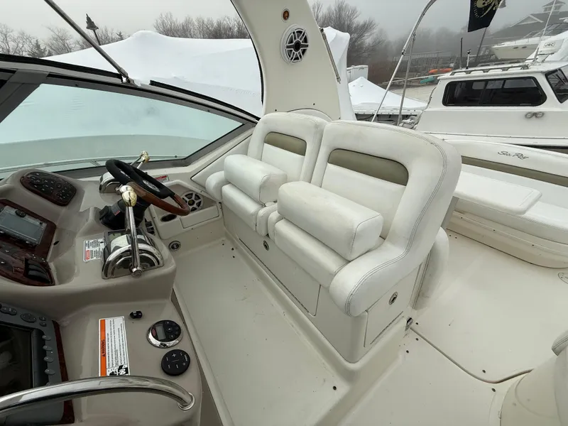Slide: The Image of 2006 Sea Ray 320 Sundancer cockpit with dual white leather seats and control panel. - 11